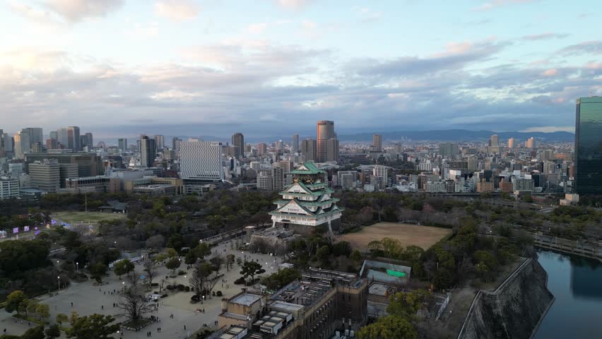 Aerial view of Osaka Castle flying over and revealing the Osaka skyline.