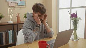 Handsome young man with beard and tattoos feeling stressed while working on laptop in a modern home interior. - Powered by Shutterstock - Get 15% off with code: PIKWIZARD15