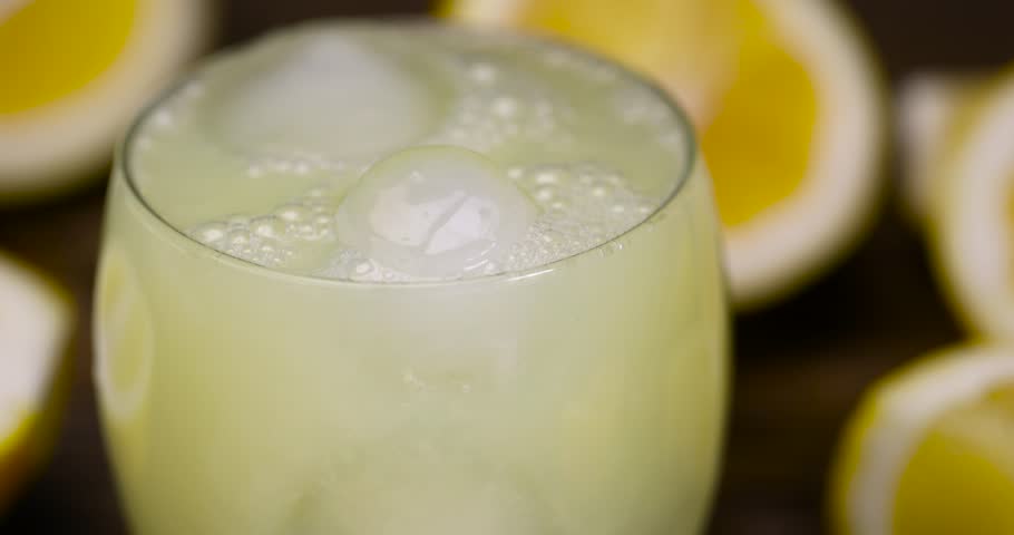 ripe sliced lemon and lemon juice with ice, ripe sliced lemon and cold juice with ice and their reflection on a wet table