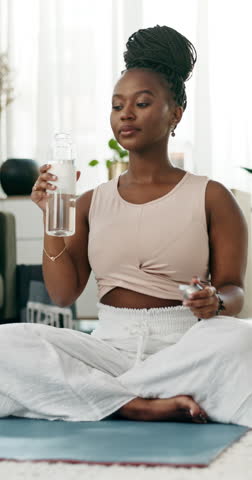 Drinking water, yoga or black woman in home with wellness, fitness or health for hydration after exercise. Thirsty African person, living room or healthy lady with liquid and incense smoke to relax