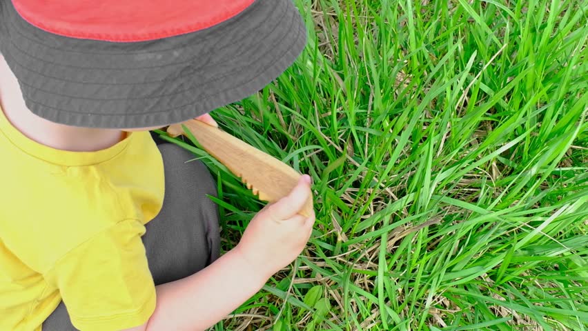 child plays with a wooden toy knife cutting grass