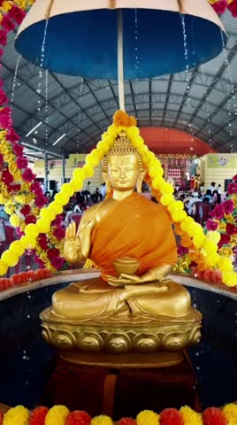 Buddha statue sitting in lotus position with falling water drops. 