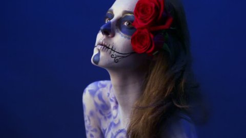 Model with rose in hair and angry make-up poses and bares her teeth in studio