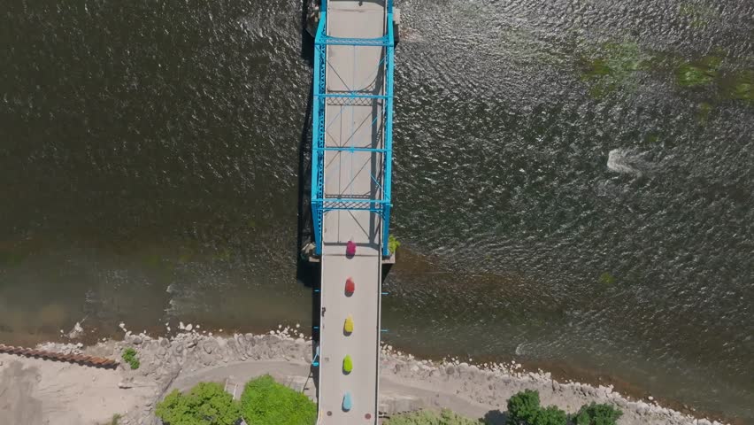 Blue bridge over Grand River in downtown Grand Rapids, Michigan with drone video overhead and tilting up to skyline.