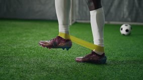 Closeup view of sportsman legs during workout with elastic band on soccer field. Professional soccer player training muscles of leg, intensive sport workout, sportive boots and gaiters, sport activity - Powered by Shutterstock - Get 15% off with code: PIKWIZARD15