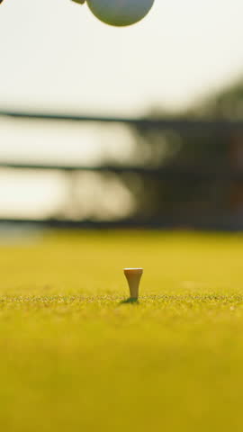 VERTICAL VIDEO. Male hand in a golf glove puts the ball on the field. Golfer placing golf ball on the tee at golf course. Close up