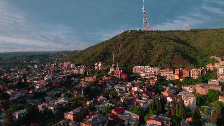 Aerial sunrise view of city with tower on hill. mtatsminda, urban landscape 