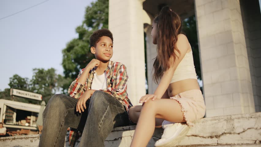 Teenagers having fun near a monument in the city park on a sunny day, socializing and relaxing