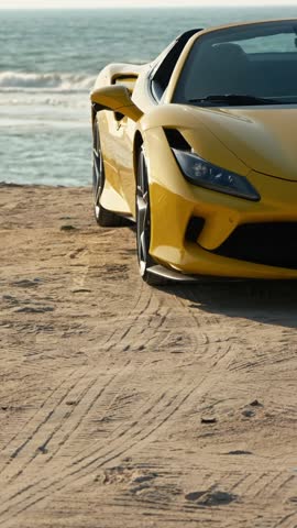 An expensive yellow sports car on a sandy seashore.