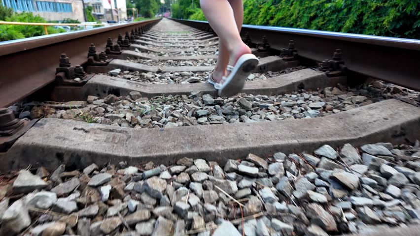 A person walks along railroad tracks in Crimea on a sunny day.