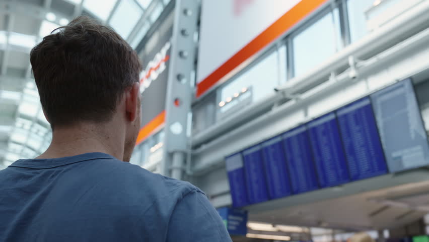 Guy looking at flight schedule board. Man in international airport looking at the flight information board, checking flights. Tourist international airport terminal flight timetable. Travel concept