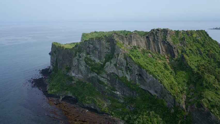An ascending drone footage of Seongsan Ilchulbong peak (Sunrise Peak) on a sunny day in Seogwipo-si city, Jeju Island, South Korea