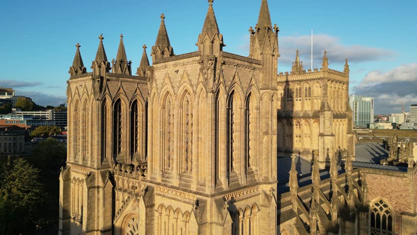 A drone view of Bristol Cathedral in England on a sunny day with city buildings around it and sky behind it