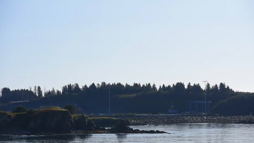 A beautiful view from the sea with a rocky beach, with mountain in the background and misty sky in Kodiak, Alaska