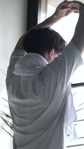 Vertical animation of the upper body of a man stretching and elongating by a window.
