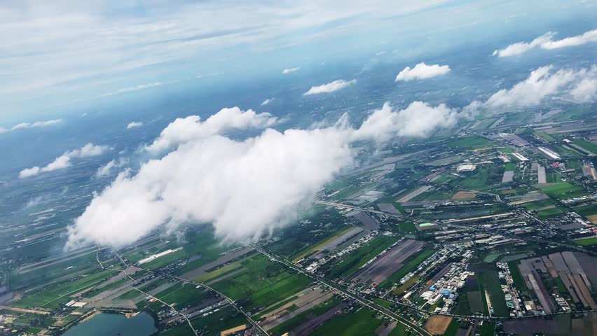 Cultivated fields, light clouds and blue sky. View through airplane porthole. 4k video footage