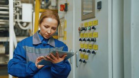 Technician engineer woman in production workshop of a modern factory adjusts equipment. Machine software, female worker enters data digital tablet. Machine setup, packaging factory, paper industry. - Powered by Shutterstock - Get 15% off with code: PIKWIZARD15
