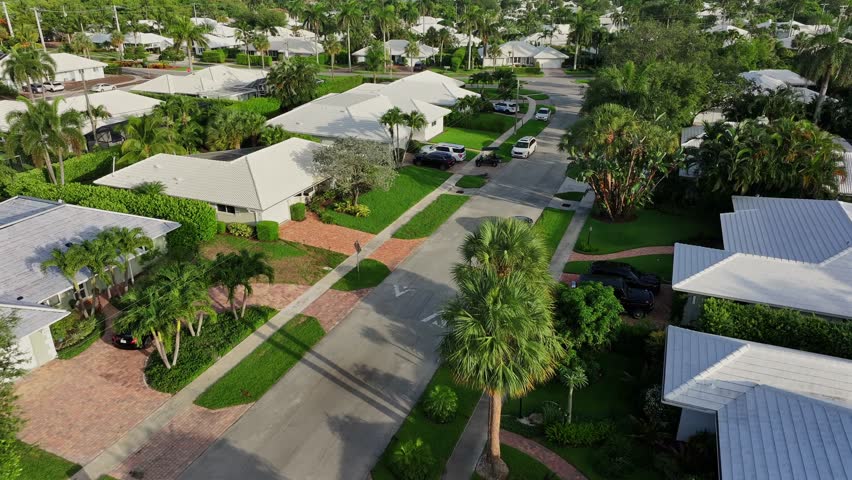 Aerial approaching shot of luxury neighborhood with villas and parking cars in Boca Raton, Florida. Birds eye shot.