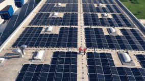 Two electricians walking on rooftop solar panel array aerial back view. Male workers wearing reflective clothing inspecting photovoltaic cells system on roof drone tracking shot - Powered by Shutterstock - Get 15% off with code: PIKWIZARD15