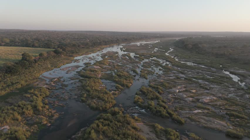 Crocodile River and sugar cane fields by Kruger Park at golden hour, aerial spin