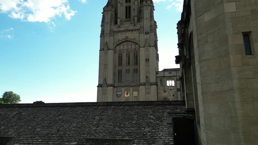 A drone shot of the historic Wills Memorial Building Tower with the sun flare in the dusk sky in the background at sunset in Bristol, England, UK