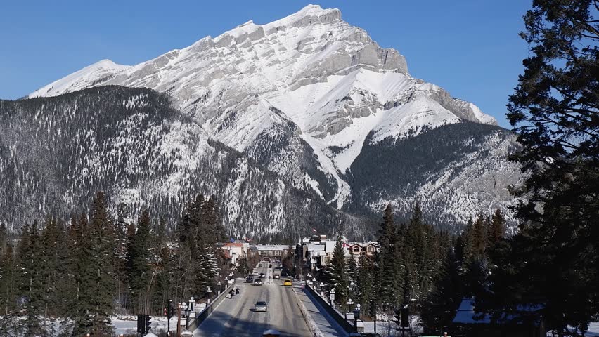 Light traffic on Banff Avenue with Cascade Mountain beyond in winter