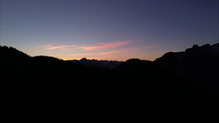Dark Silhouette from Mountains and Forests with Sunrise in Background. Bludenz, Austria, Europe. 4k Aerial View