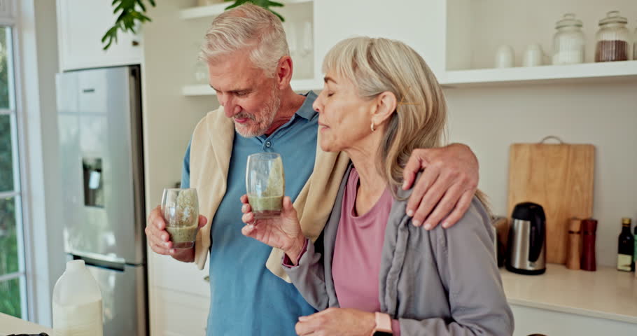 Senior couple, smoothie and smile in kitchen with toast for workout, wellness and supplements in home. People, woman and man with protein, green juice and drink for benefits, hug and fitness in house