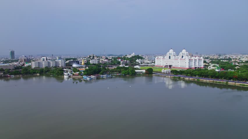 aerial view of telangana secretariate and martyrs memorial with reflections in hussain sagar lake, hyderabad, telangana, india, 4k push in drone shot