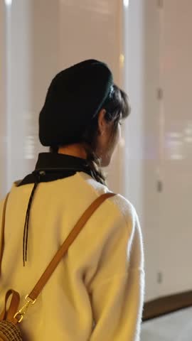 Vertical slow-motion video of a young and cute Taiwanese woman in her 20s walking amidst beautiful illuminations at night in a high-end shopping mall area of Xinyi District, Taipei, Taiwan