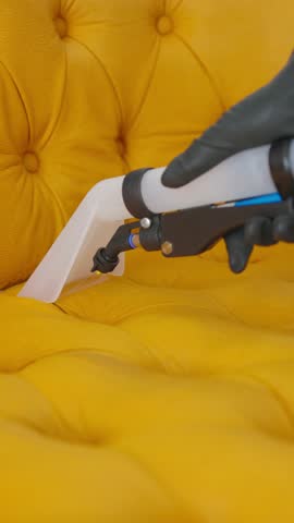 Close-up wet cleaning of upholstered furniture, with water sprayed from a vacuum cleaner, vertical footage.
