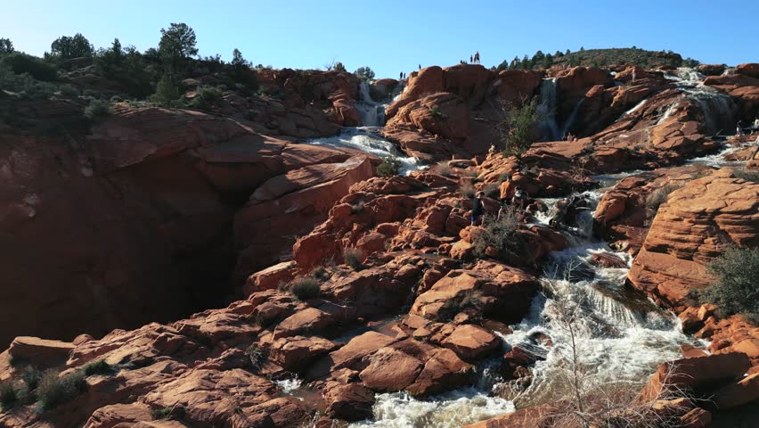 A drone shot of the Dunclock Falls in Utah with people around it.