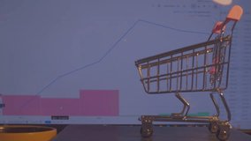 Modern economy. Business concept. A small empty shopping cart stands against the background of a computer monitor on which economic data is changing. Close-up. Shallow depth of field. - Powered by Shutterstock - Get 15% off with code: PIKWIZARD15