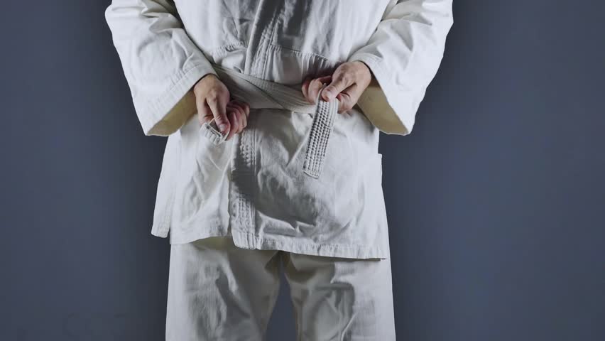 A man standing in white kimono progressing from white to black belt in martial art skills