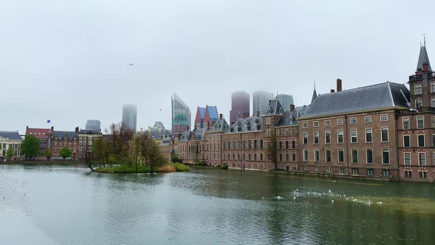 The Binnenhof House of Parliament and the Hofvijver lake with skyscrapers in the background on a foggy day in The Hague, Netherlands