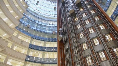 Elevators ride at multilevel building with transparent roof, view from below in motion