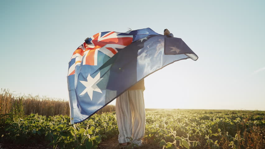 Australian little kid - child patriot with national flag on sky background at sunset. Australia celebration banner, Anzac day, commonwealth
