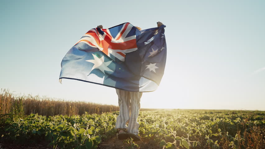 Australian little kid - child patriot with national flag on sky background at sunset. Australia celebration banner, Anzac day, commonwealth