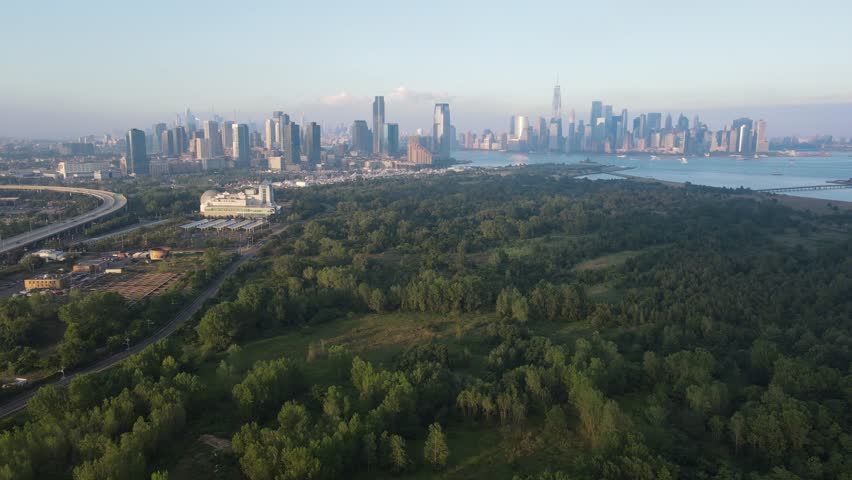 An aerial view of Liberty State Park with New York and New Jersey cities skylines in the background at sunrise, USA