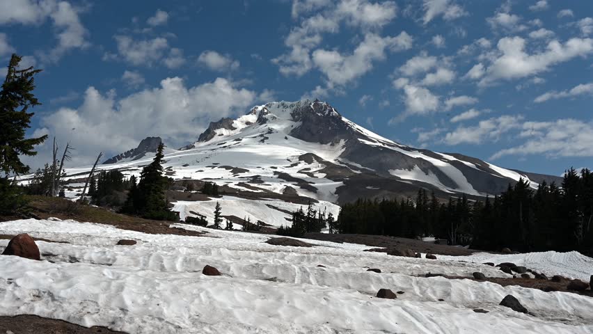 A timelapse footage of a snow groomer preparing the ski slopes with Mt Hood in the background on a sunny day in Oregon, USA
