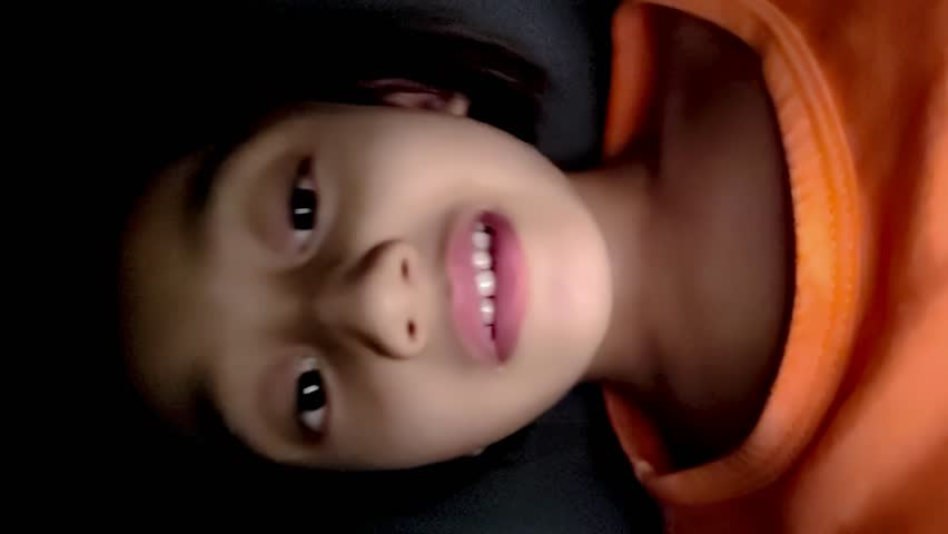 A little girl is making a funny face, a self-portrait. 4K Vertical