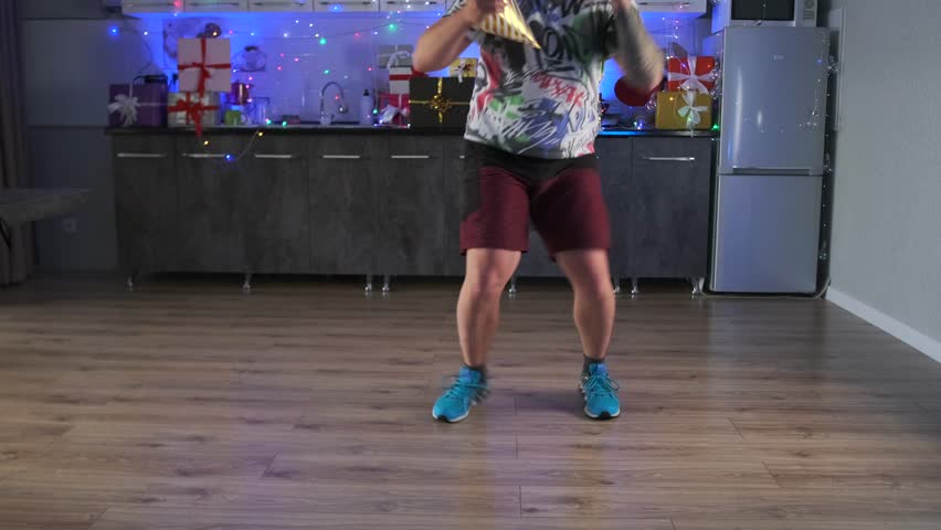 Feet of man in blue sports shoes fast dancing on the wooden floor of a modern kitchen, close-up.