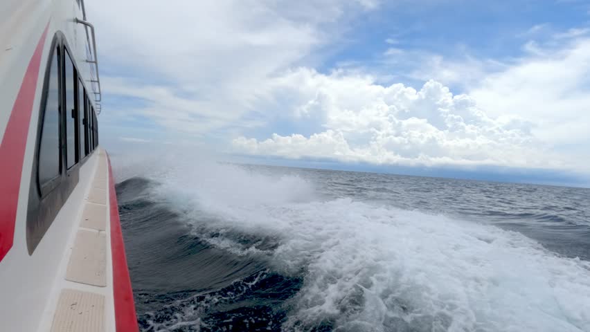 Side view from Boat Fast Moving on a Choppy Ocean Waves Under a Cloudy Blue Sky Slow Motion. Travel by Speedboat Journey, Experiencing the Sheer Force of Open Sea 4k