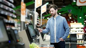 Male customer using a self-service cashier checkout in a supermarket. Shopper scanning produce items using at grocery store self serve cash register. cashier terminal man pay for products online - Powered by Shutterstock - Get 15% off with code: PIKWIZARD15