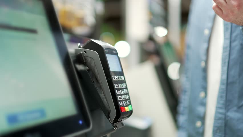 Close up man At Counter Buy electronic payment supermarket mall smartphone close-up male hand with mobile phone in hands pay paid for purchases in stores Contactless NFC Terminal Closeup card reader