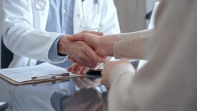Doctor and patient handshake in clinic setting above the glass table. Medicine concept trust and agreement - Powered by Shutterstock - Get 15% off with code: PIKWIZARD15