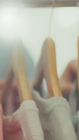 Vertical monitor. A fashion-conscious housewife reviews her wardrobe, choosing suitable outfits. She studies the clothes on the racks to create a modern look
