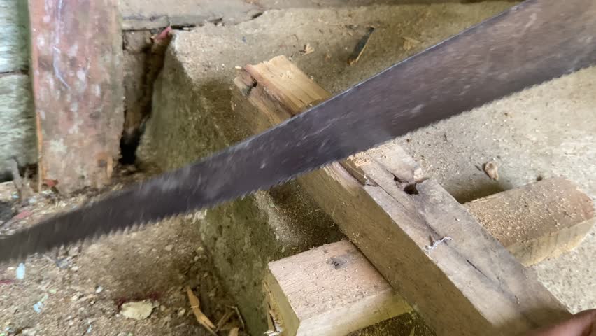 Carpenter cutting lumber with a hand saw. A man is sawing wood using a manual saw.