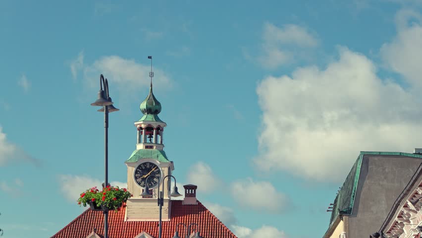 Clock Tower in Rauma, Finland on a Sunny Day	A close-up view of the clock tower in Pori, Finland, with a blue sky and white clouds in the background. The tower has a green roof and a clock face on the