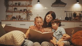 Mother and her two children sit on couch while daughter reads aloud from book. Concept of family bonding and love for reading. Nurturing learning and emotional connection at home - Powered by Shutterstock - Get 15% off with code: PIKWIZARD15